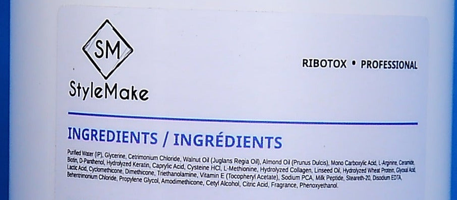 Close-up of a white product label with the StyleMake SM logo and 'INGREDIENTS / Éingrés' text, showing a partial blue bottle edge on the left and right sides.
